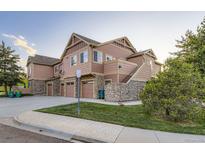 A well-maintained townhouse with tan and brown siding and stone accents and attached garages at 5757 S Algonquian Way # E, Aurora, CO 80016