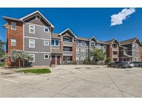 Apartment building featuring gray siding, brick accents, multiple floors, and a convenient parking area at 14251 E 1St Dr # 305, Aurora, CO 80011