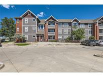 Three-story condo building with gray siding, brick accents, and convenient parking at 14251 E 1St Dr # 305, Aurora, CO 80011