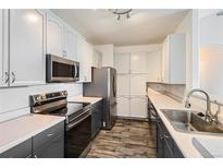 Modern kitchen features stainless steel appliances, gray lower cabinets, white upper cabinets and attractive floors at 14251 E 1St Dr # 305, Aurora, CO 80011
