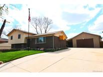 Charming home with a well-maintained lawn, a detached garage, and an American flag waving in the yard at 11823 Williams Way, Northglenn, CO 80233