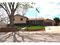Charming two-story home featuring a brick facade, landscaped front yard, and an American flag at 11823 Williams Way, Northglenn, CO 80233