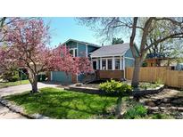 Charming exterior of a blue home showcasing a blossoming tree, green lawn, and well-maintained landscaping at 15962 E Lehigh Cir, Aurora, CO 80013