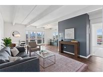 Bright living room features exposed beams, hardwood floors, and floor to ceiling sliding glass doors with city views at 1441 N Humboldt St # 505, Denver, CO 80218