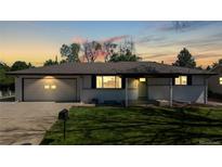 Charming home with lush lawn, attached garage, and lovely curb appeal at sunset at 6931 W 75Th Pl, Arvada, CO 80003