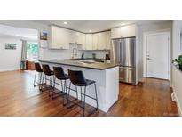 Bright kitchen featuring white cabinets, stainless steel appliances, and a breakfast bar with seating for four at 6931 W 75Th Pl, Arvada, CO 80003