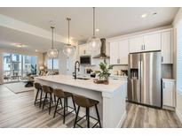 Modern kitchen with white cabinets, stainless steel appliances, and a large center island with seating at 1759 Peak Loop, Broomfield, CO 80023