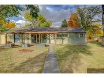 Ranch style home with a covered patio and well-manicured lawn at 10125 W 8Th Pl, Lakewood, CO 80215