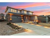 Beautiful two-story home with landscaped front yard, gray garage door, and a stunning sunset in the background at 9527 Loveland Way, Arvada, CO 80007