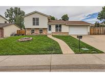 Charming two-story home featuring a well-manicured lawn, walkway, brick accents and attached two-car garage at 380 S 25Th Ave, Brighton, CO 80601