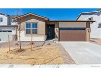 Charming single Gathering home with a beige stone and vinyl exterior and a two-car garage at 9141 Telluride Ct, Commerce City, CO 80022