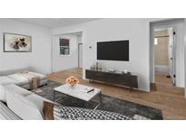 Bright living room featuring a large sectional sofa, modern decor, and wood laminate flooring at 2621 S Federal Blvd, Denver, CO 80219