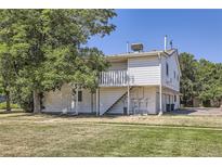 White siding covers this two-story home with a balcony and grassy lawn at 62 Newark St # D, Aurora, CO 80012