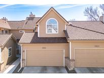 Charming home featuring two-car garage, tan siding, beautiful tiled roof, and lovely arched window above the garage at 5976 S Jellison St # E, Littleton, CO 80123