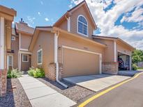 Inviting tan two-story townhome featuring a two-car garage and walkway with lovely landscaping at 5976 S Jellison St # E, Littleton, CO 80123