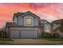 Two-story home featuring a three-car garage and sunset sky at 3823 S Uravan St, Aurora, CO 80013