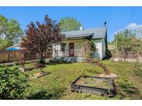 Charming front yard featuring mature trees, green lawn, and a quaint blue home with inviting red door at 4635 Teller St, Wheat Ridge, CO 80033