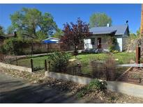 Charming single-story home with a well-manicured front yard, mature trees, and an inviting red front door at 4635 Teller St, Wheat Ridge, CO 80033