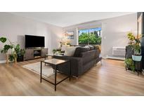 Cozy living room featuring neutral walls, wood flooring, and a sliding glass door to the balcony at 7040 E Girard Ave # 207, Denver, CO 80224
