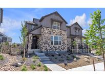 Charming townhouse with a stone facade, landscaped front yard, and modern architectural details at 8145 Monte Vista Cir, Littleton, CO 80125