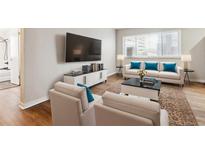 Bright living room features hardwood floors, comfy seating, and a large TV at 1101 Bellaire St # 108, Denver, CO 80220