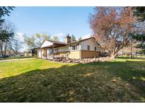 Spacious ranch-style home with a lush lawn, mature tree, and covered porch, perfect for outdoor living at 625 Ammons St, Lakewood, CO 80214