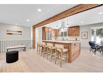 Bright kitchen features a spacious island with bar seating, stainless steel appliances, and wood beam accents at 1189 Lodgepole Dr, Evergreen, CO 80439