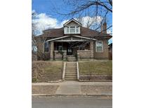 Charming two-story brick home featuring a covered porch, dormer, and well-maintained landscaping at 2090 Birch St, Denver, CO 80207