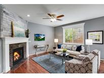 Cozy living room featuring a fireplace, modern ceiling fan, and comfortable seating area with natural light at 602 Mathews Way, Erie, CO 80516