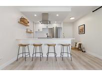 Modern kitchen featuring stainless steel appliances, white cabinetry, and stylish breakfast bar with seating at 955 Eudora St # 1606, Denver, CO 80220