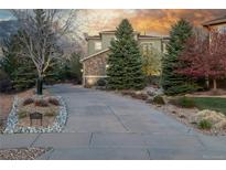Inviting home with a long driveway, lush greenery, and beautiful stone accents at 20148 E Windy Pine Pl, Parker, CO 80134