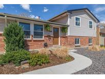 Charming home exterior with brick accents, updated siding, manicured landscaping, and a welcoming walkway to the front door at 6611 Lamar St, Arvada, CO 80003