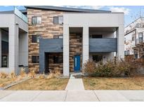 Modern home with brick and stucco exterior, a bright blue front door and a well-maintained lawn at 2150 Eliot St, Denver, CO 80211
