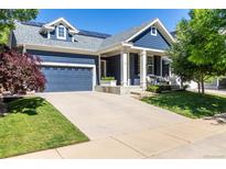 Charming blue two-story home with landscaped yard, solar panels, and covered porch with seating at 1038 Mircos St, Erie, CO 80516