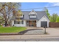 Charming two-story home featuring dormer windows, a manicured lawn, and a cozy covered front porch at 12212 W 60Th Pl, Arvada, CO 80004