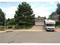 Ranch-style home with brick driveway, white garage door, landscaped yard, and an RV in front at 13126 W Warren Cir, Lakewood, CO 80228