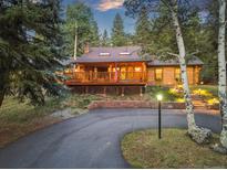 Beautiful log cabin-style home with a spacious deck, stone accents and an inviting driveway nestled in a wooded area at 34100 Woodland Dr, Evergreen, CO 80439