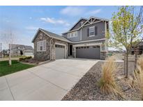 Stunning two-story home featuring a stone facade, gray siding, and a spacious three-car garage at 6802 S Uriah St, Aurora, CO 80016
