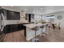 This bright kitchen features dark cabinets, stainless steel appliances and a large island with bar stool seating at 6802 S Uriah St, Aurora, CO 80016
