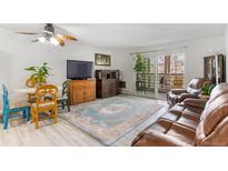 Bright living room with hardwood floors, ceiling fan, and sliding glass doors to the balcony at 595 S Alton Way # 1C, Denver, CO 80247
