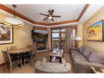 Comfortable living room featuring a stone fireplace, television, and a balcony with scenic mountain views at 1521 Ski Hill Rd # 8318, Breckenridge, CO 80424
