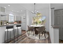 Bright dining area featuring hardwood floors, a modern chandelier, and a window view at 8422 S Upham Way # G60, Littleton, CO 80128
