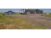 Gravel driveway leads to a charming single-story home with a detached garage and parked RV at 11809 Pass Me By Rd, Strasburg, CO 80136