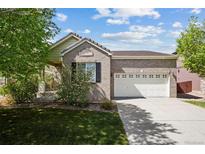 Charming brick home boasts a well-maintained lawn, mature trees, and a two-car garage at 15594 E 97Th Ave, Commerce City, CO 80022