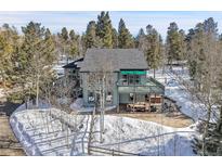Charming exterior featuring a spacious patio, hot tub, outdoor seating, and a deck, surrounded by scenic trees and snowy landscape at 11647 Leavenworth Dr, Conifer, CO 80433