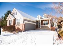 Charming two-story home featuring brick accents, a welcoming front porch, gray siding, and a gray two car garage at 8387 Fig St, Arvada, CO 80005