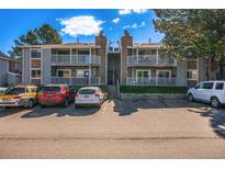 Condominium exterior featuring balconies, stone accents, parking spaces, and manicured green spaces at 904 S Walden Way # 203, Aurora, CO 80017