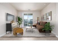 Cozy living room features a comfortable brown sofa and sliding doors to a balcony with neighborhood views at 4100 Albion St # 523, Denver, CO 80216
