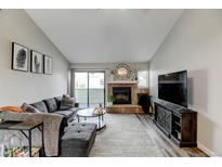 Inviting living room featuring a stone fireplace and sliding glass doors for natural light at 4108 S Rifle Way, Aurora, CO 80013