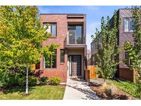 Modern brick home with a small balcony, landscaped front yard, and a stylish front door at 1833 E Jewell Ave, Denver, CO 80210